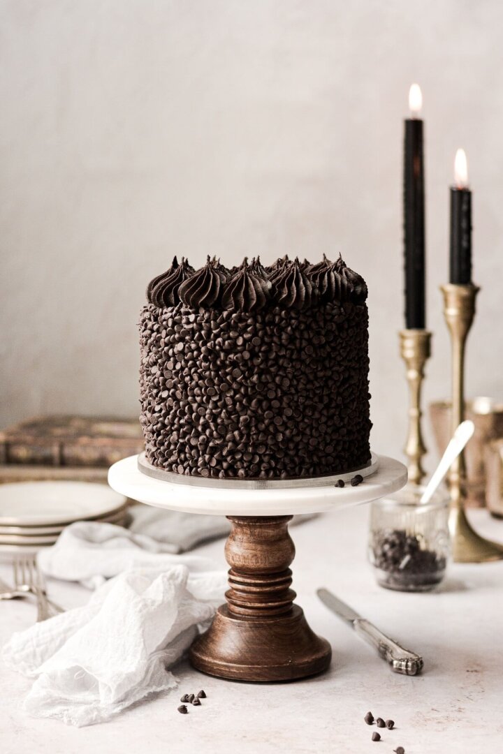 Chocolate truffle cake on a marble and wood cake stand.