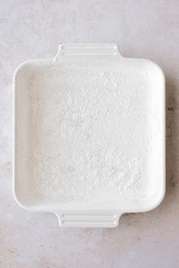A white baking dish dusted with powdered sugar.