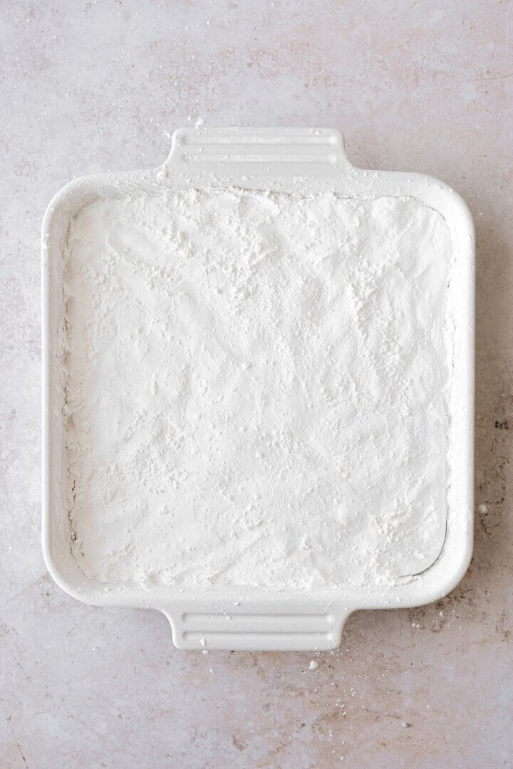 Vanilla bean marshmallow spread into a baking dish and dusted with powdered sugar.