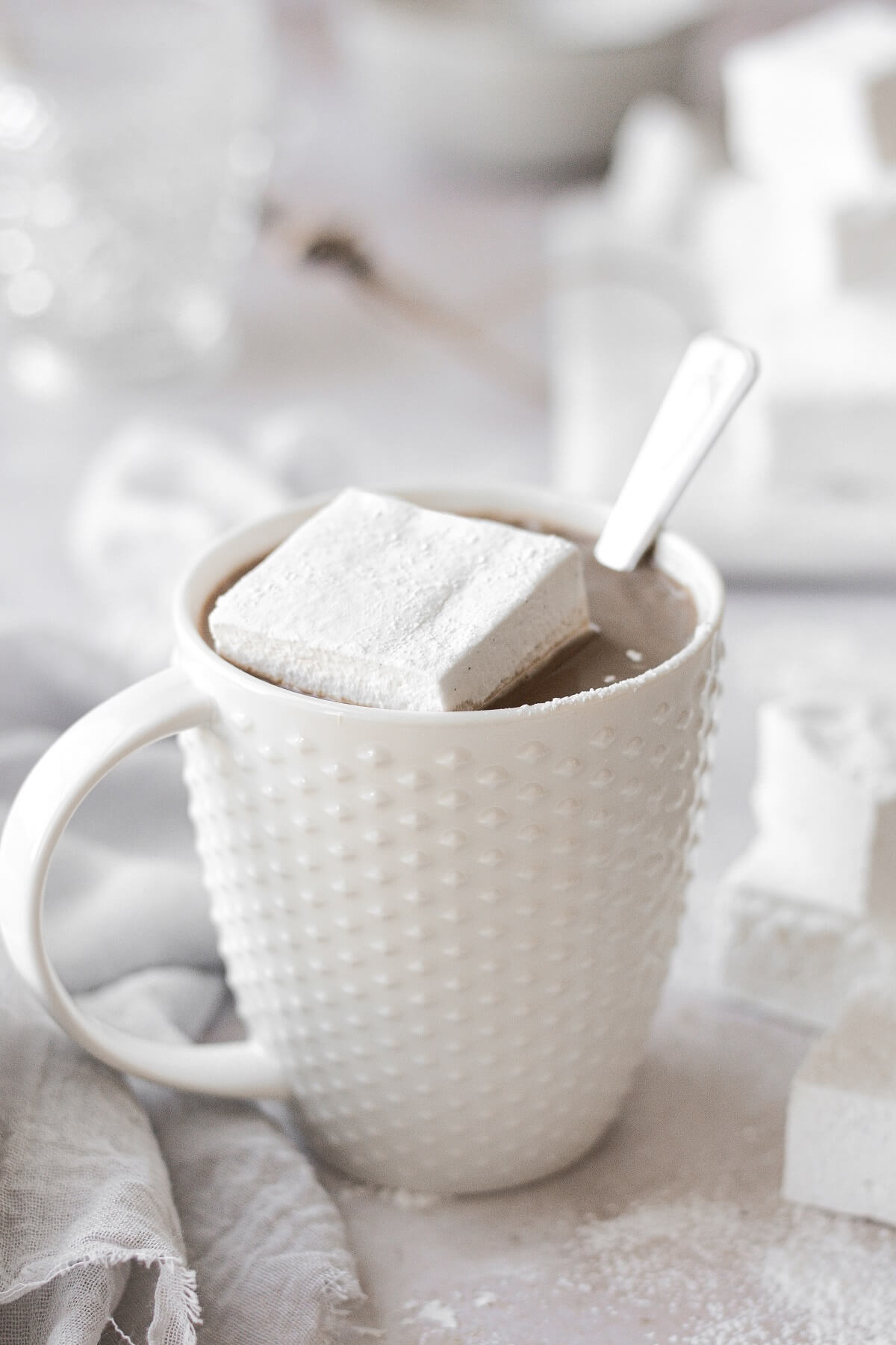 A homemade marshmallow in a white mug filled with hot chocolate.