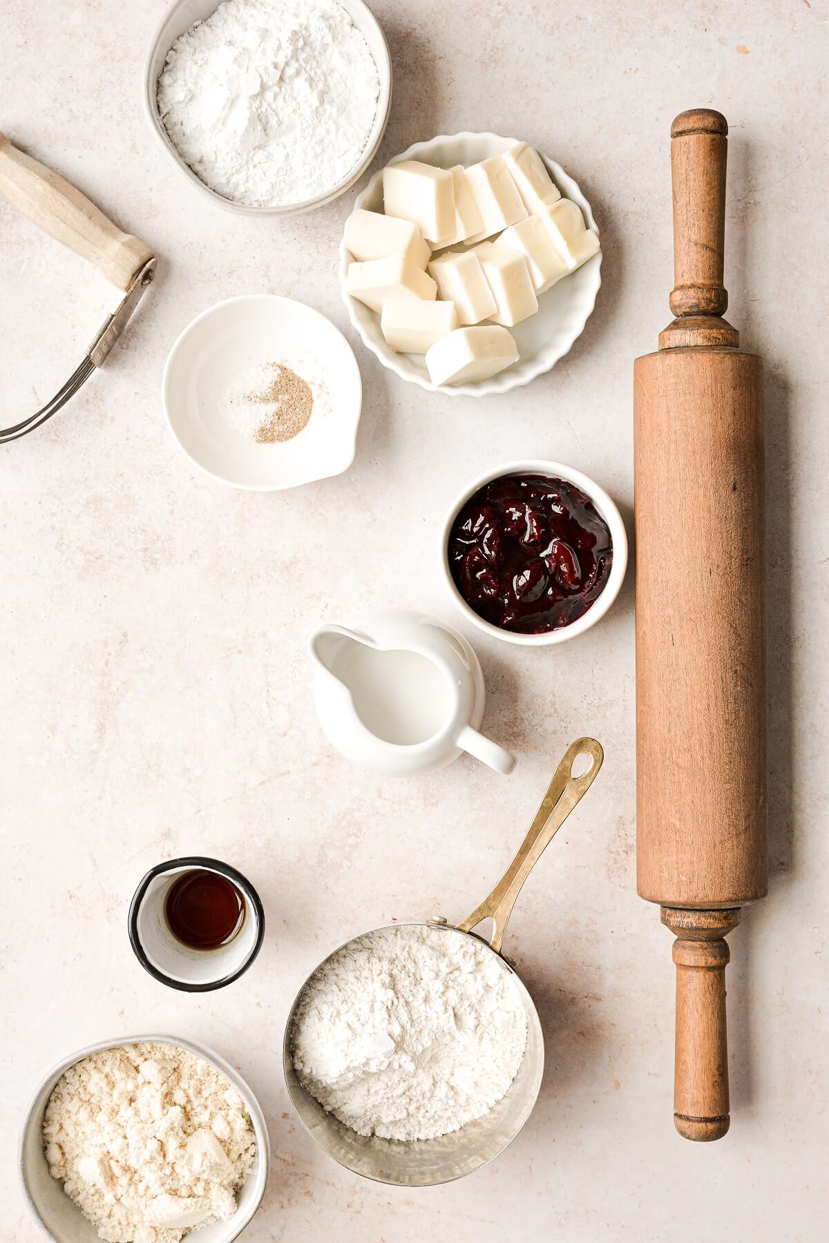 Ingredients for making linzer cookies next to a wooden rolling pin.
