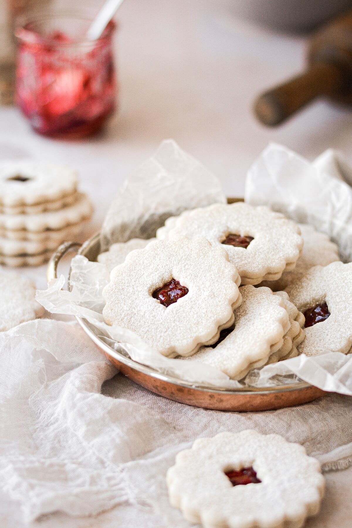 Linzer cookies filled with cherry jam piled into a copper tray.