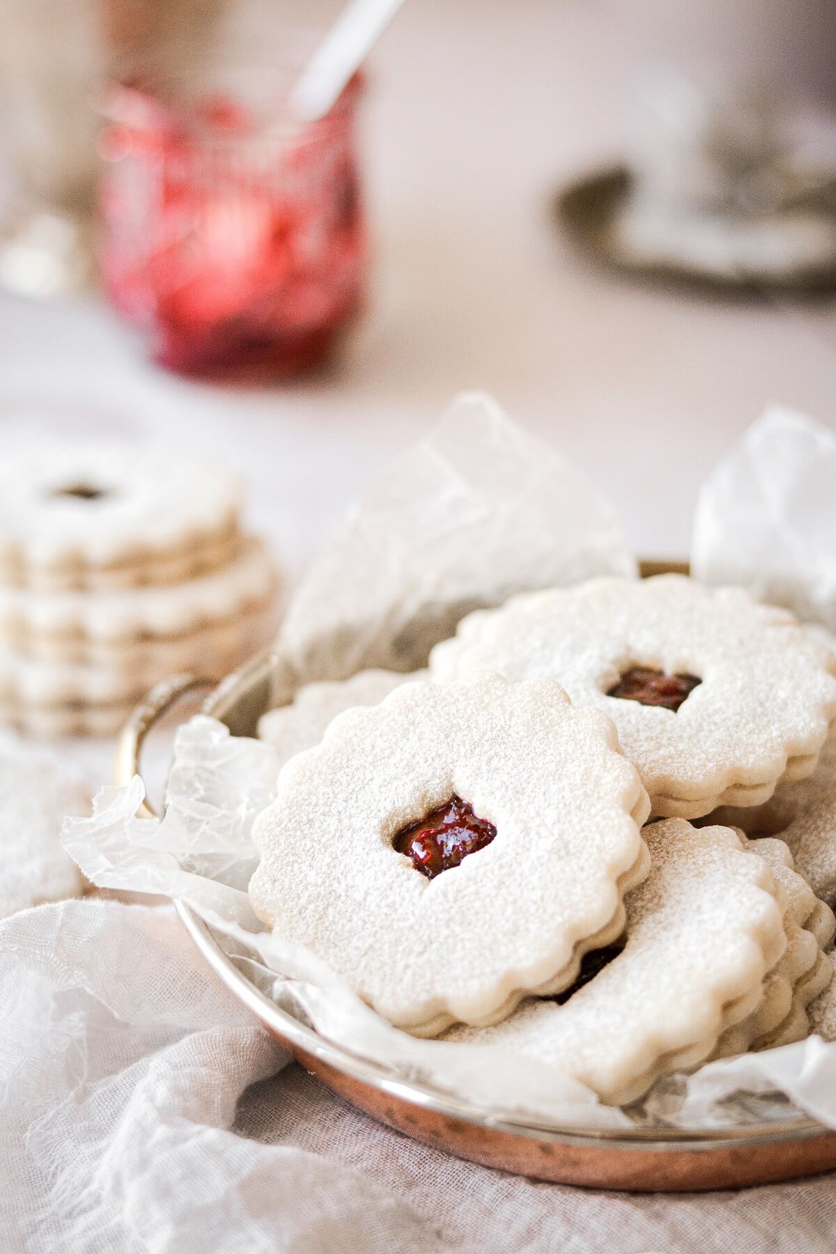 Linzer cookies filled with cherry jam piled into a copper tray.
