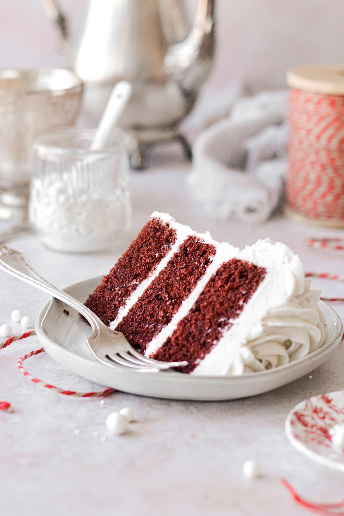 A slice of red velvet cake on a plate with a vintage silver fork.