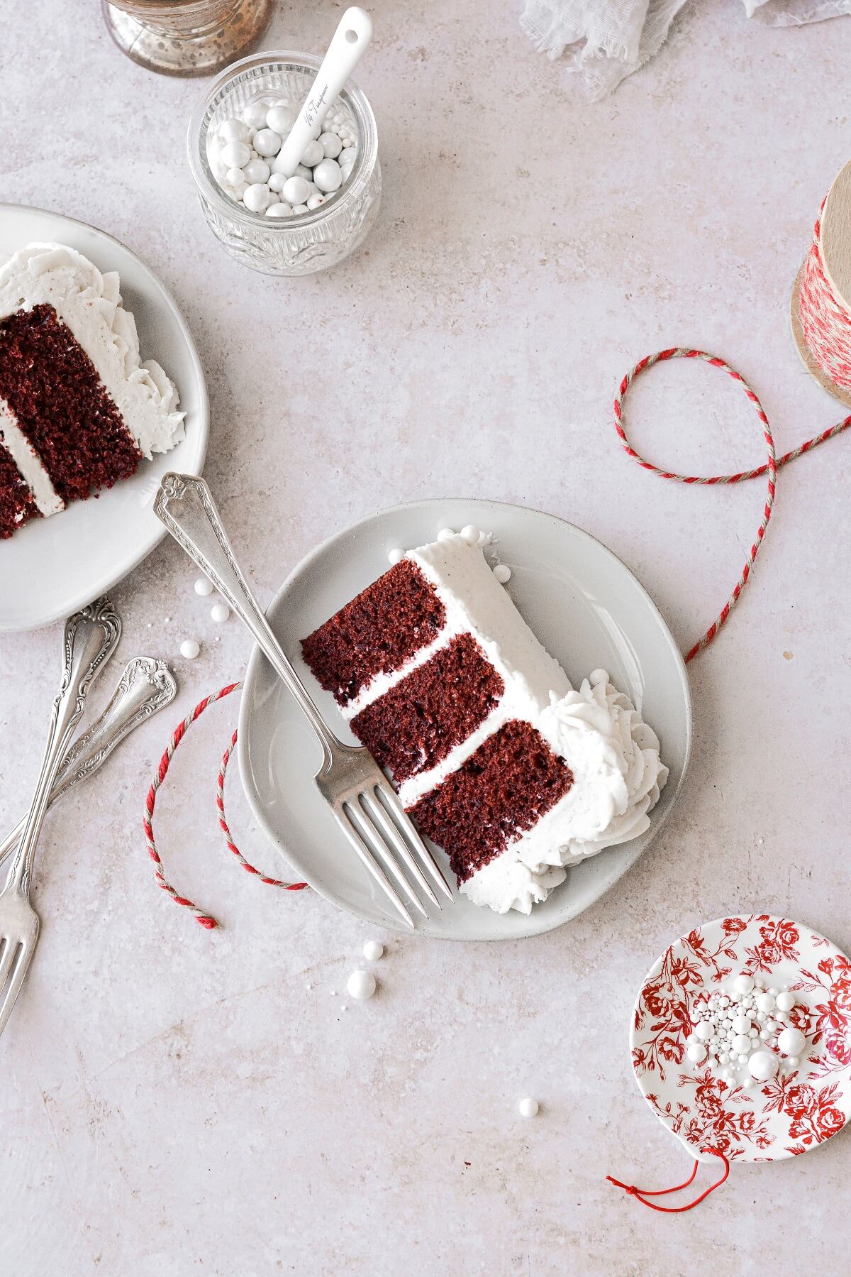 Slices of red velvet cake, with a jar of white sugar pearls and red twine.