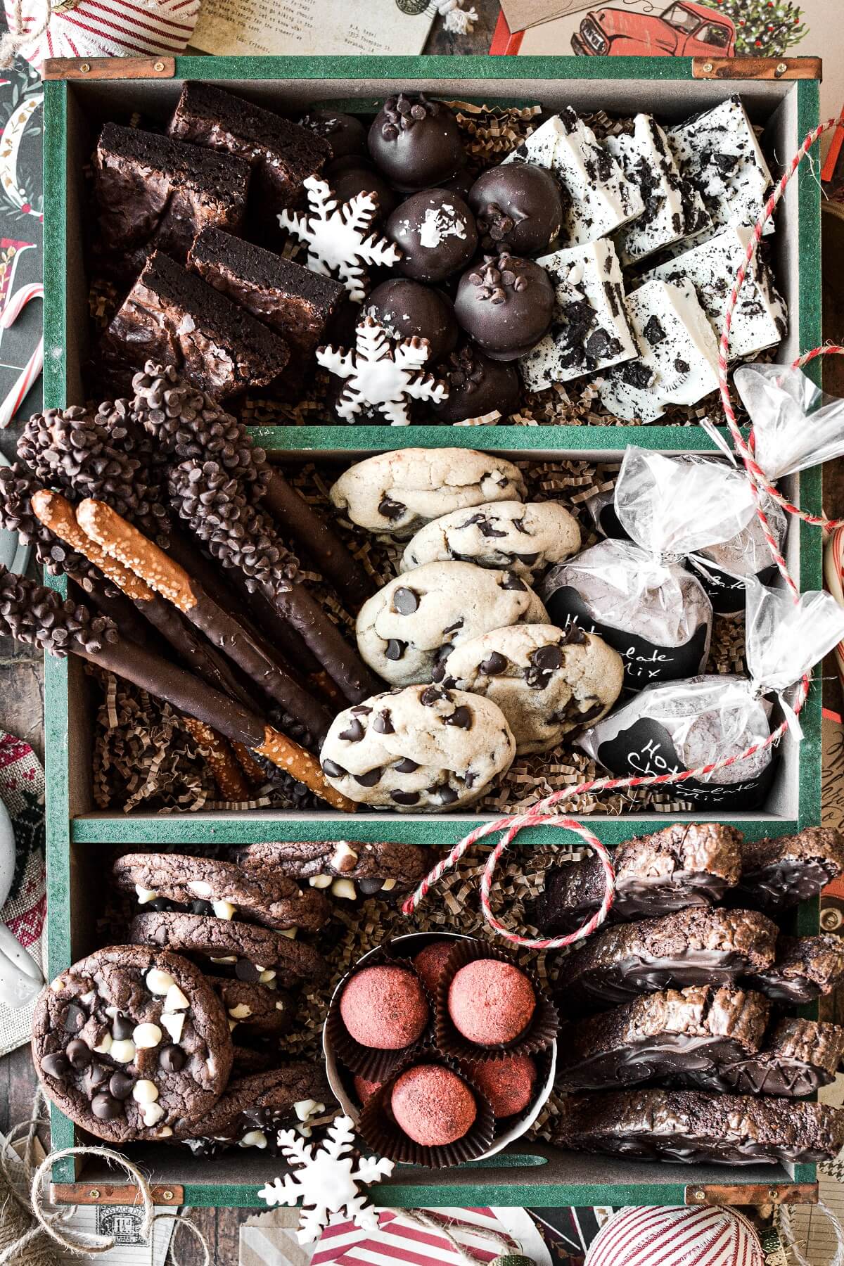 A green wooden box filled with an assortment of chocolate cookies and treats for Christmas.