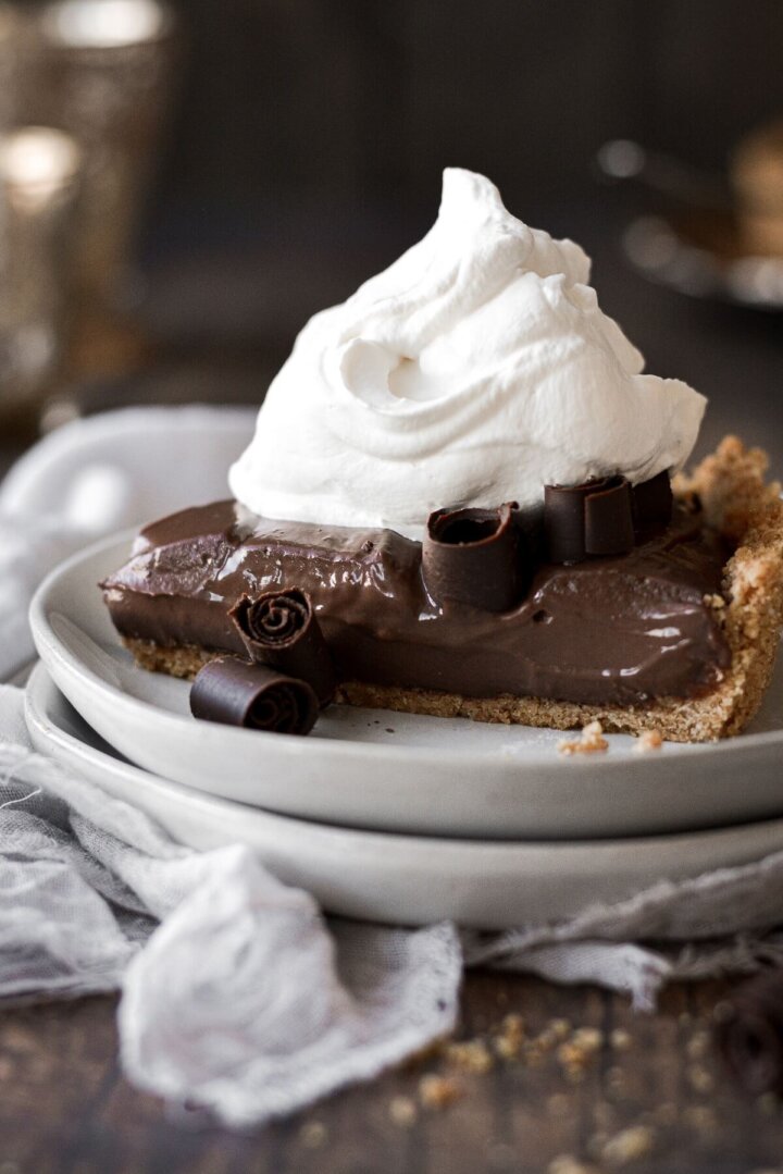 A piece of chocolate cream pie topped with whipped cream and chocolate curls.