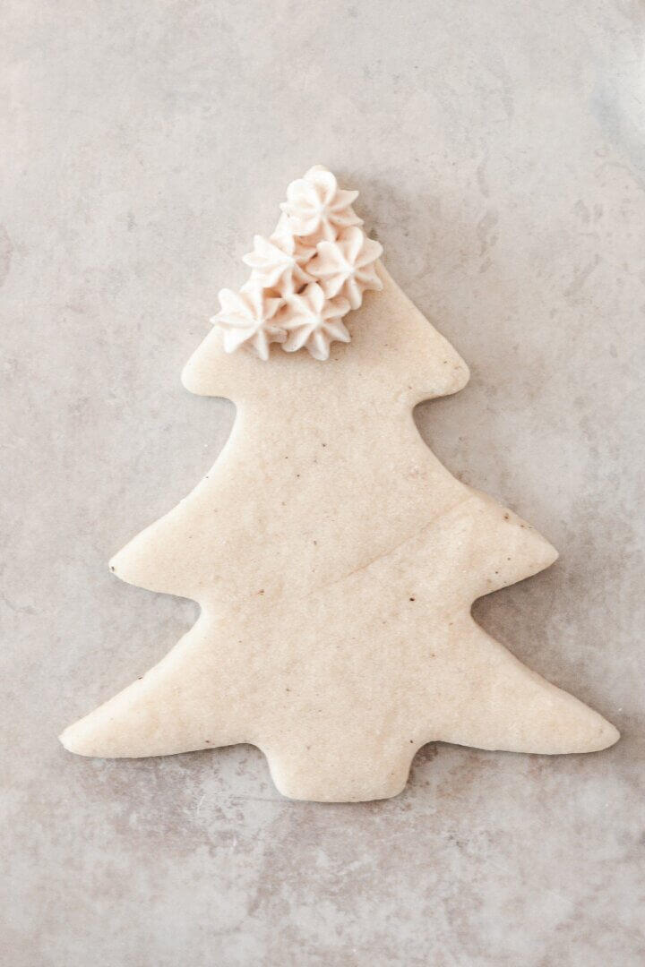 Buttercream stars piped onto a Christmas tree cookie.