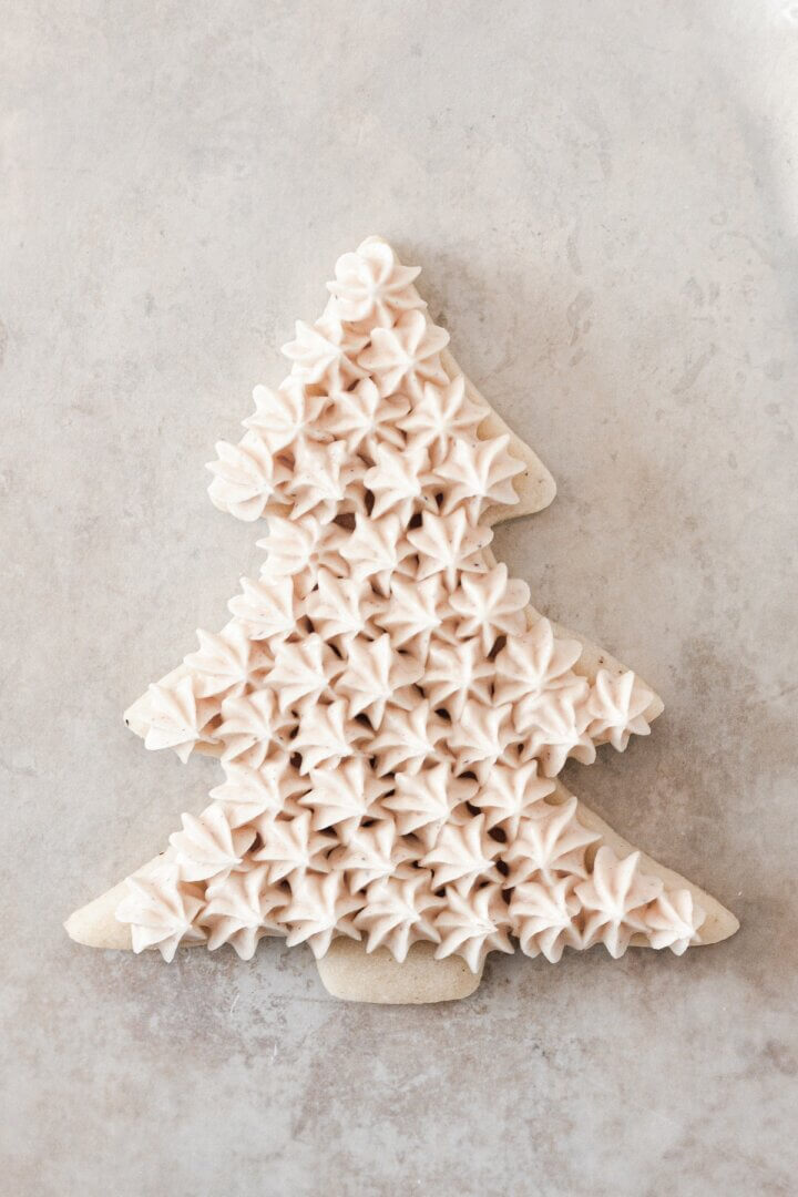 Buttercream stars piped onto a Christmas tree cookie.