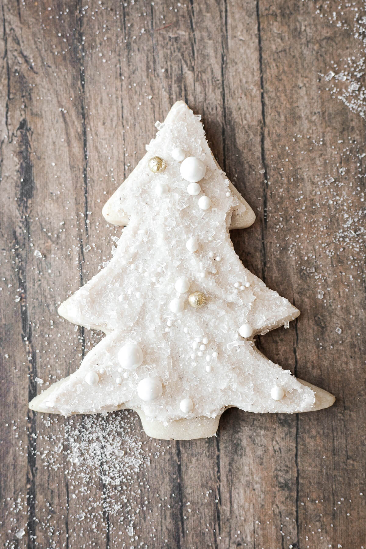 A Christmas tree cookie with sugar pearls and sparkling sugar.