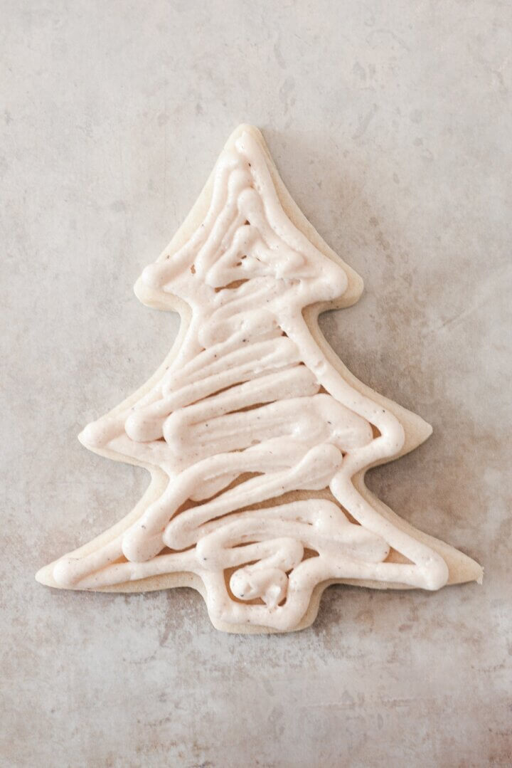 Buttercream spread onto a Christmas tree cookie.
