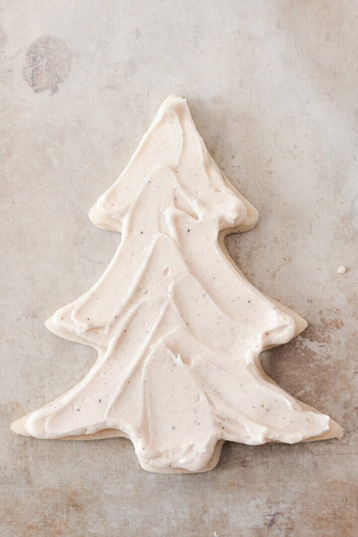 Buttercream spread onto a Christmas tree cookie.