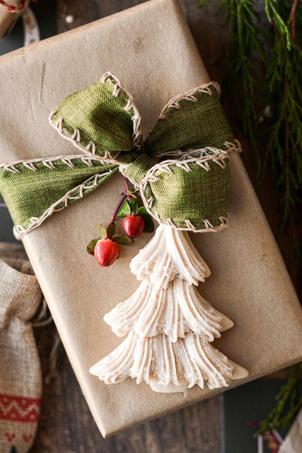 A Christmas tree cookie sitting on a present tied with green ribbon.