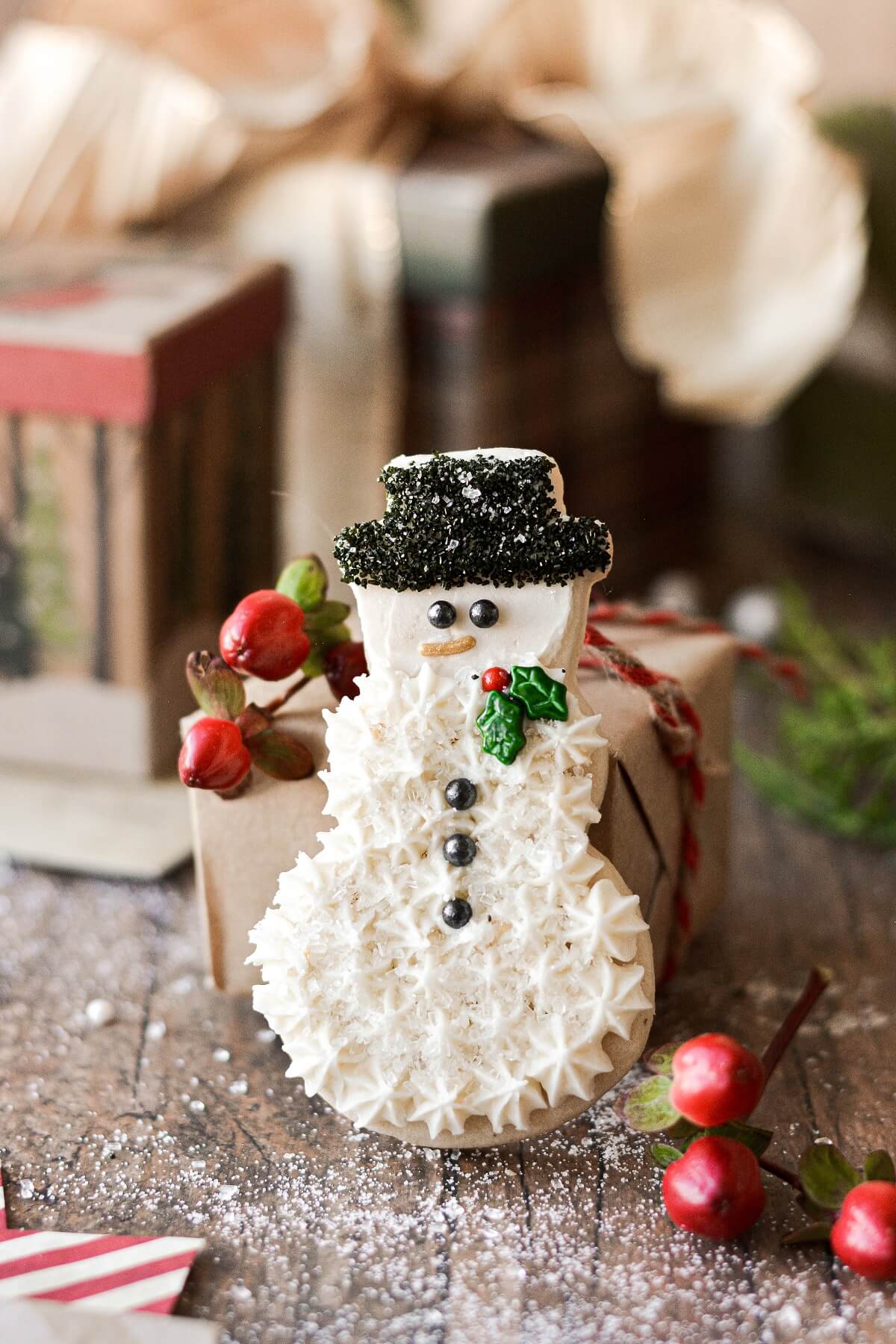 A snowman sugar cookie leaning against a small Christmas present.