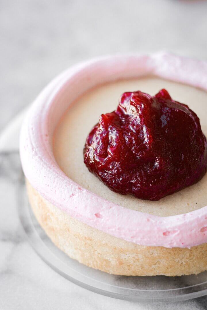 A vanilla cake being filled with cranberry jelly.
