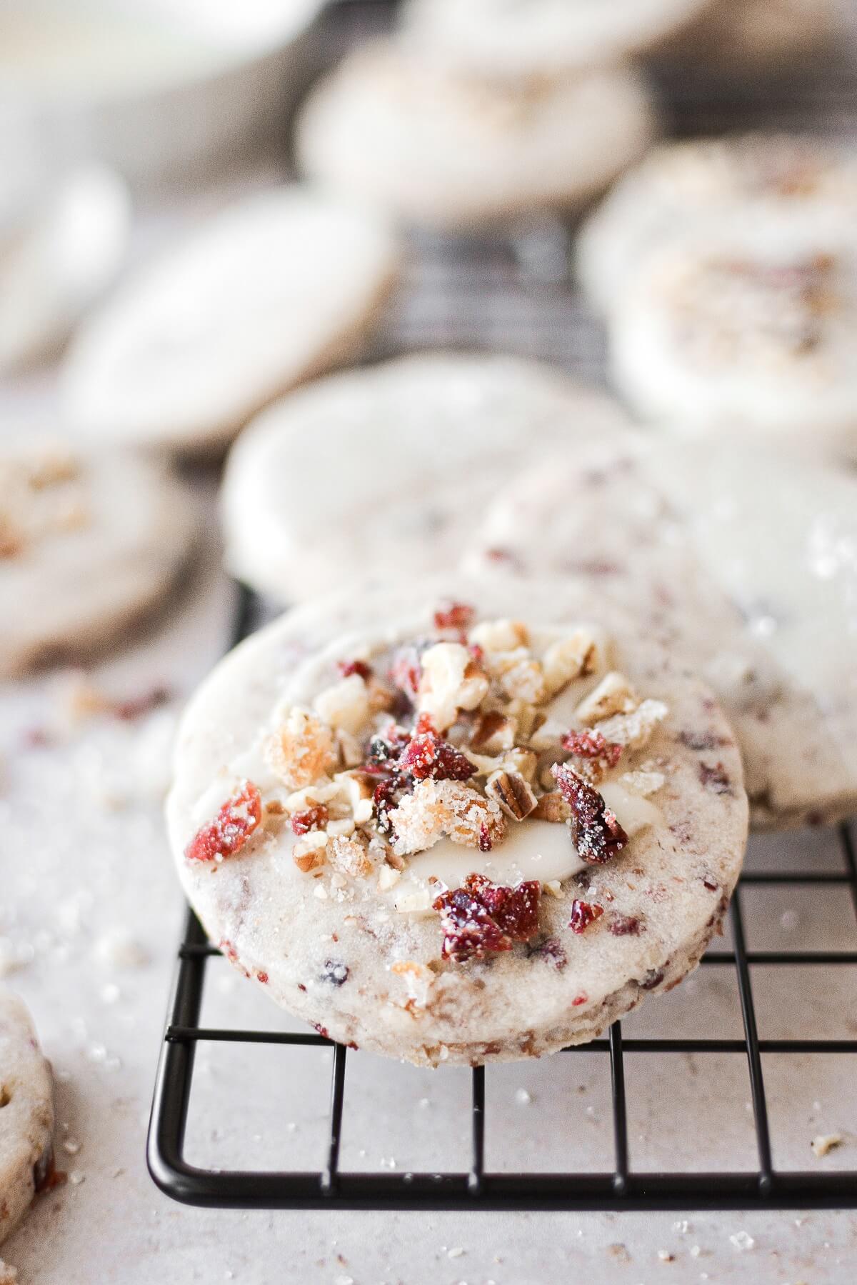 A cranberry pecan shortbread cookie on a black cooling rack.