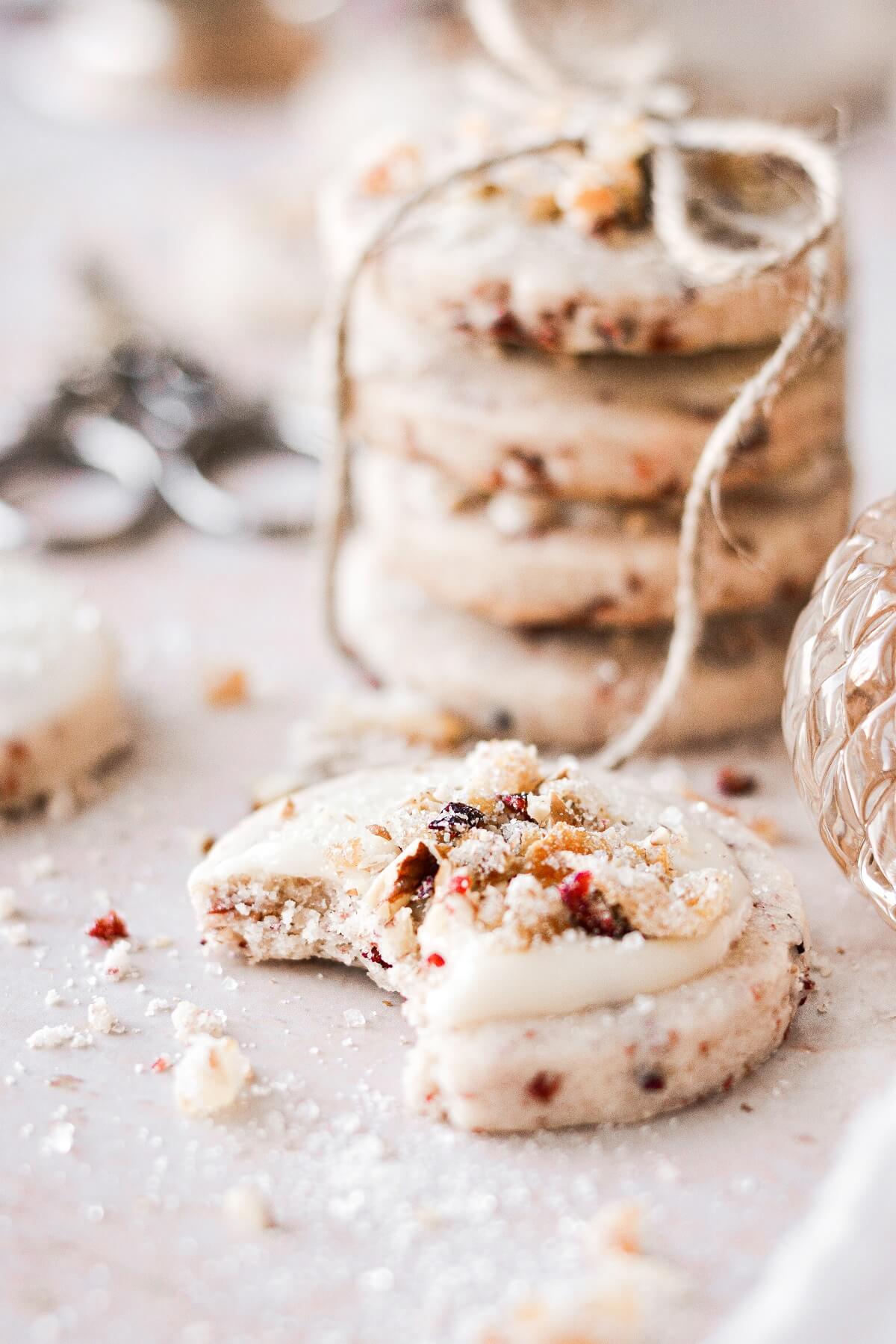 A cranberry pecan shortbread cookie with a bite taken.