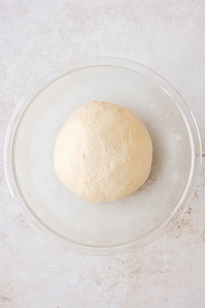 Bread dough rising in a glass bowl.