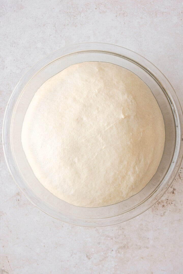 Bread dough rising in a glass bowl.