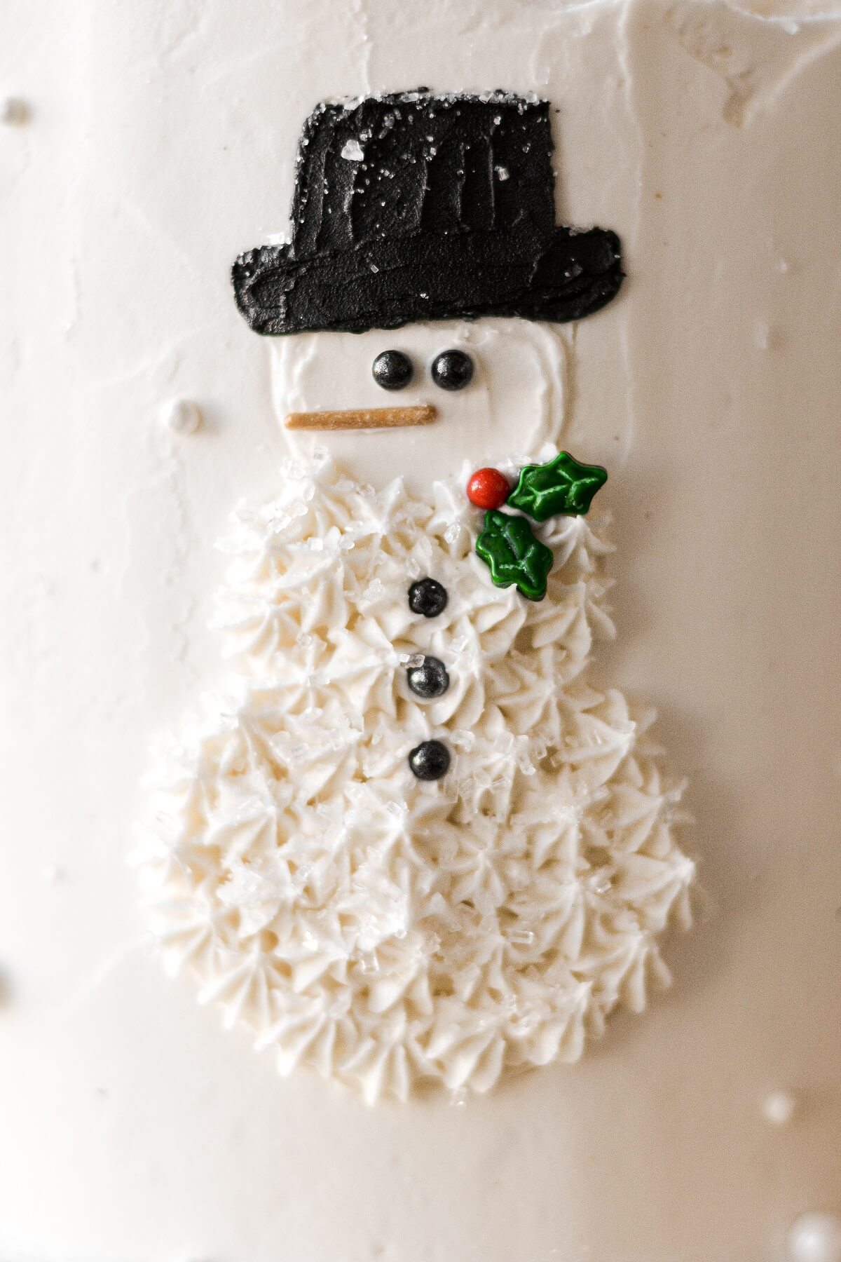 A buttercream snowman design on the side of a layer cake.
