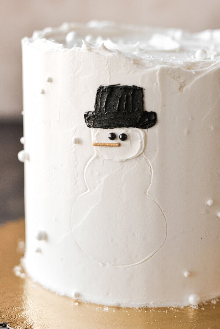 The hat and face of a snowman on the side of a layer cake.