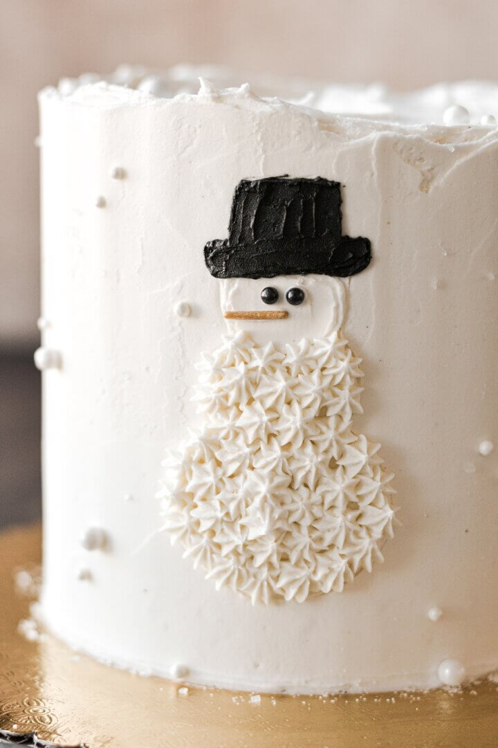 A snowman design on the side of a cake.