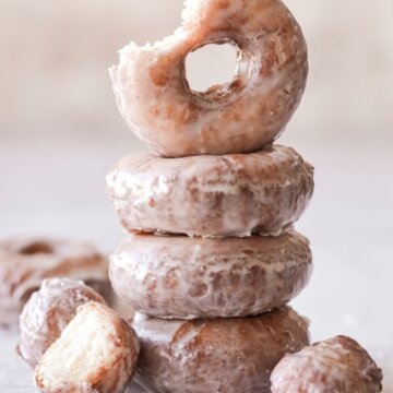 A stack of old fashioned sour cream doughnuts, one with a bite taken.