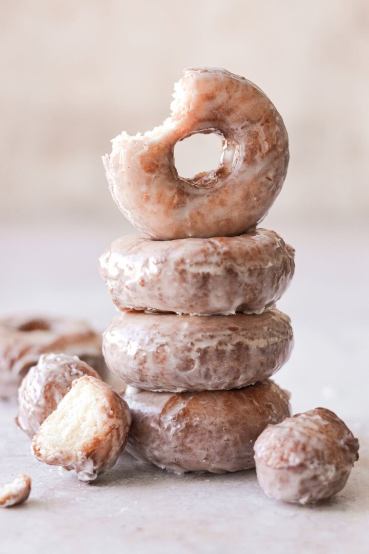 A stack of old fashioned sour cream doughnuts, one with a bite taken.