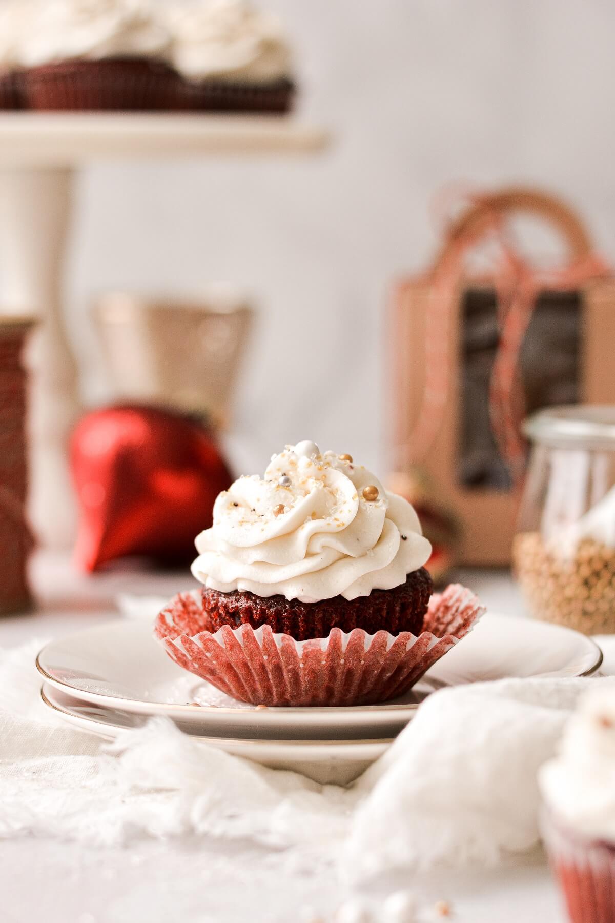 A red velvet cupcake with gold and silver sprinkles, and the wrapper pulled back.