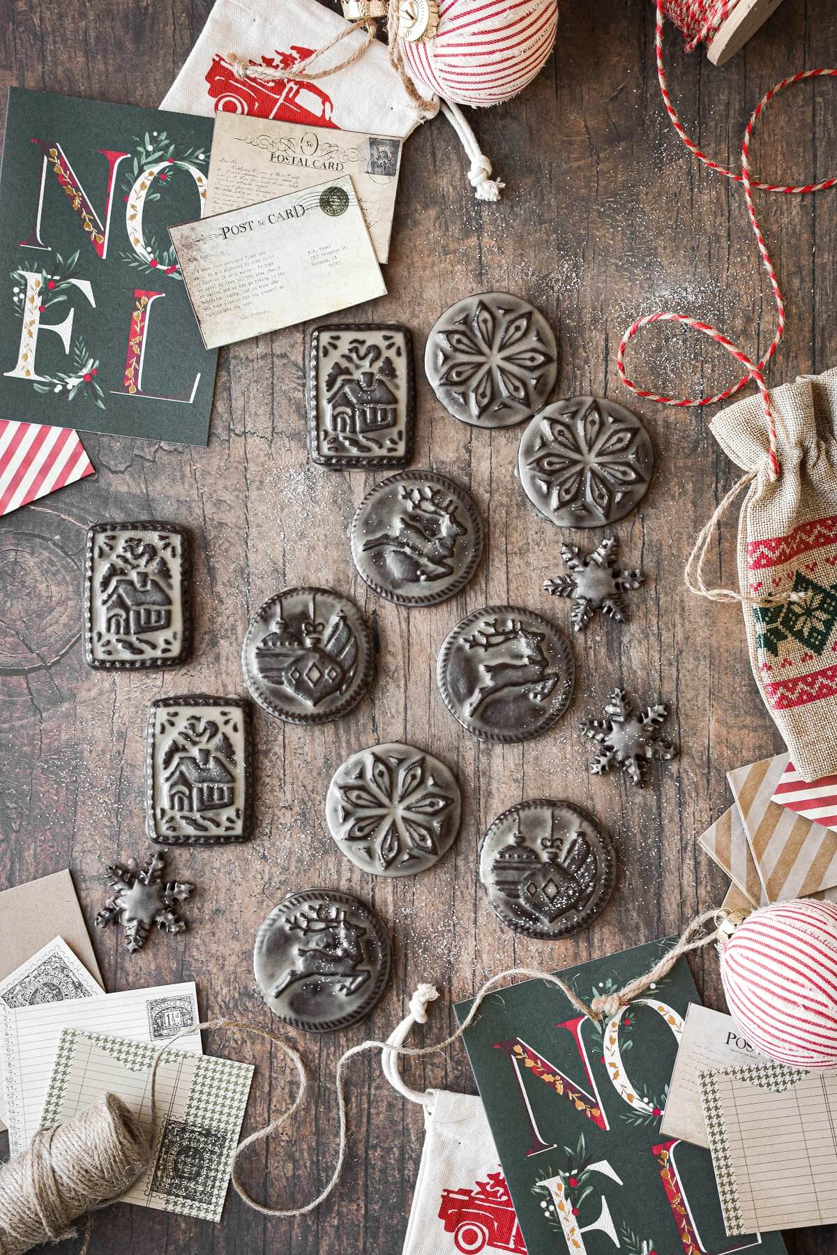 Stamped chocolate shortbread cookies with Christmas designs, surrounded by Christmas cards and twine.