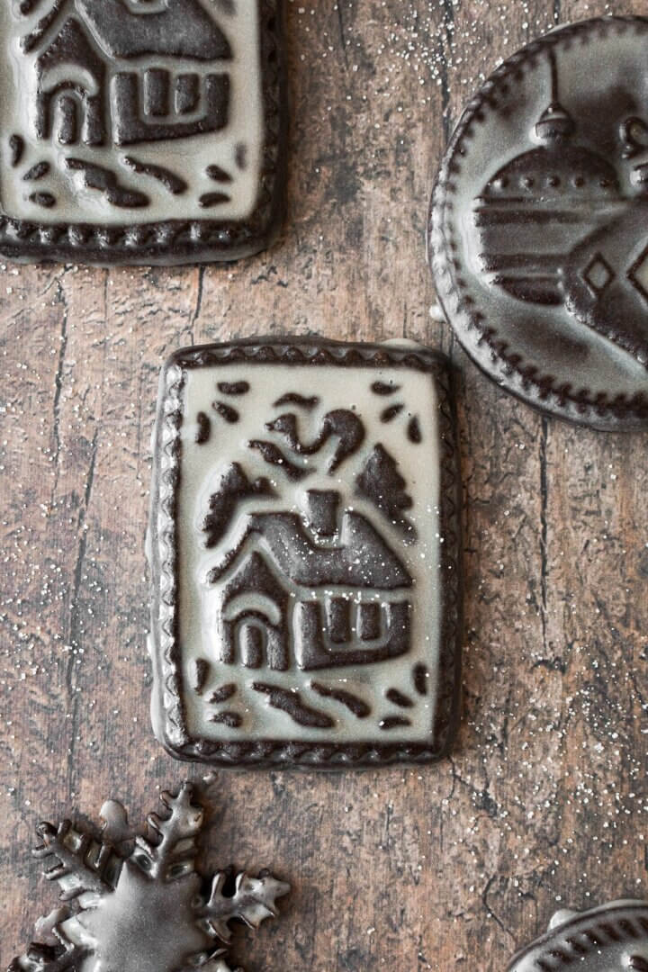 Chocolate shortbread cookies with Christmas designs stamped on them, glazed with icing.