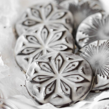Starry nights stamped chocolate cookies glazed with icing, arranged in a silver dish.