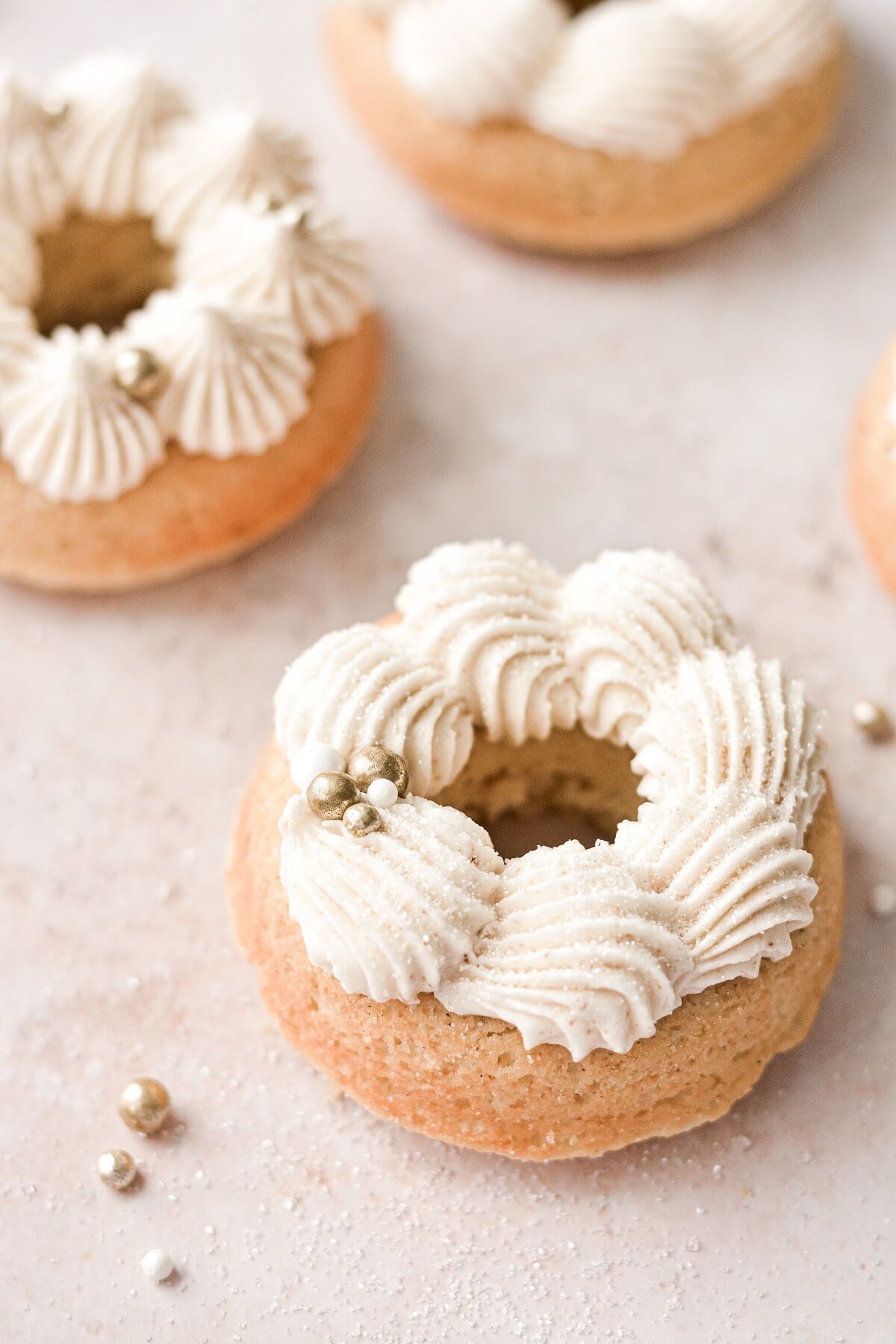 Baked vanilla cake doughnuts with piped buttercream and gold sprinkles.