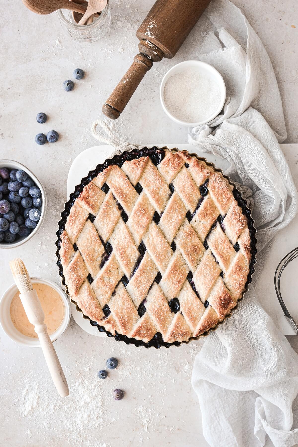 A blueberry lattice pie on a marble board.