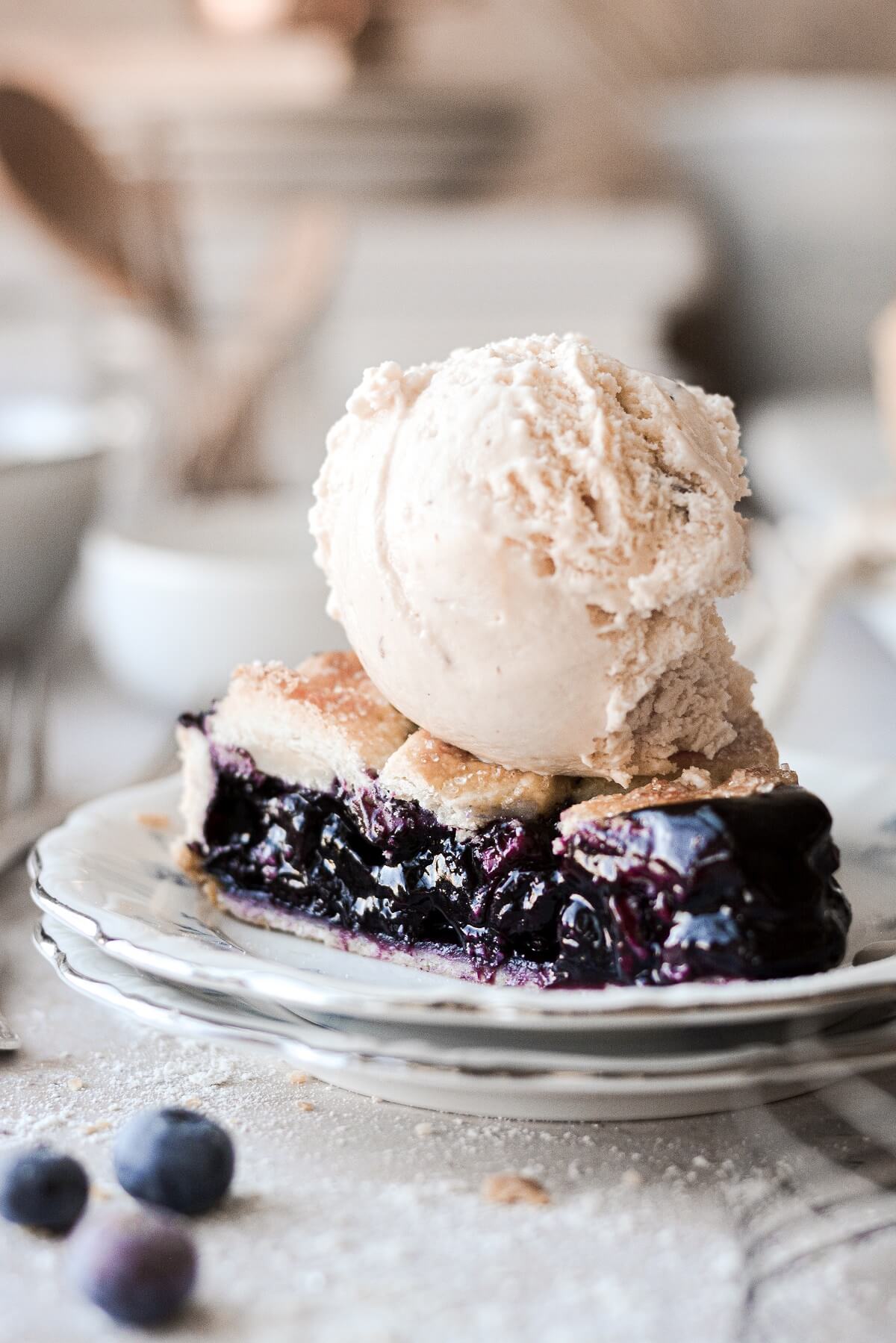 A slice of blueberry pie topped with a scoop of ice cream.