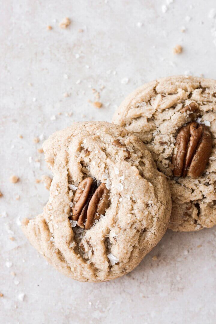 Butter pecan cookies with a bite taken out of one.