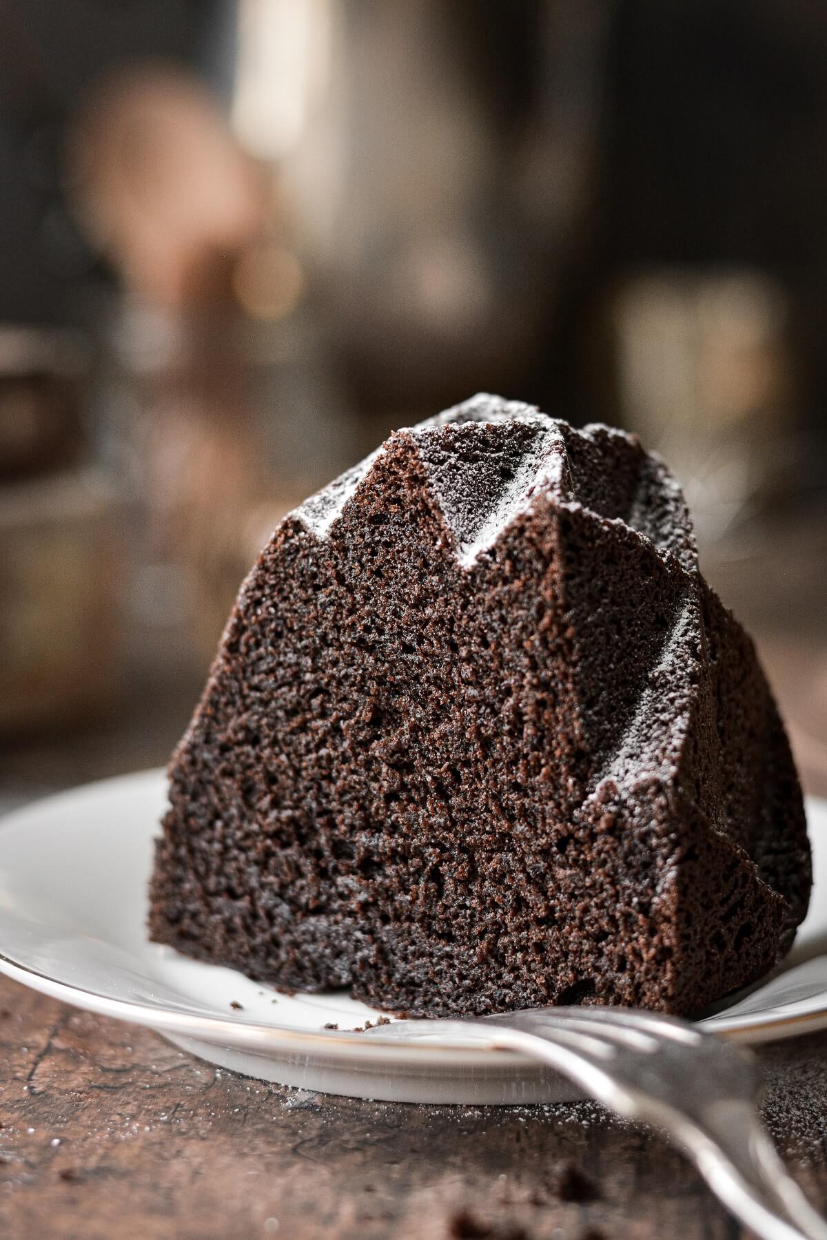 A piece of chocolate bundt cake dusted with powdered sugar.