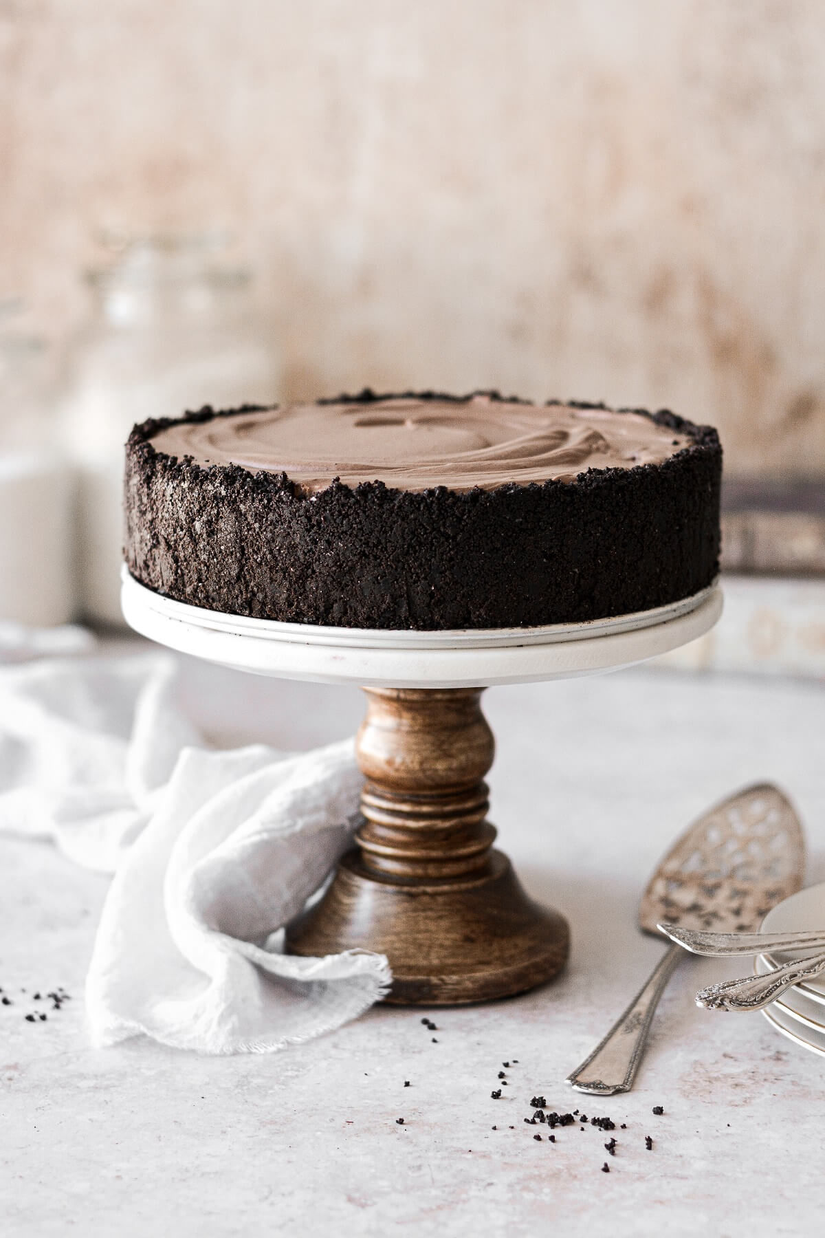Chocolate cheesecake in a chocolate crust on a wood and marble cake stand.
