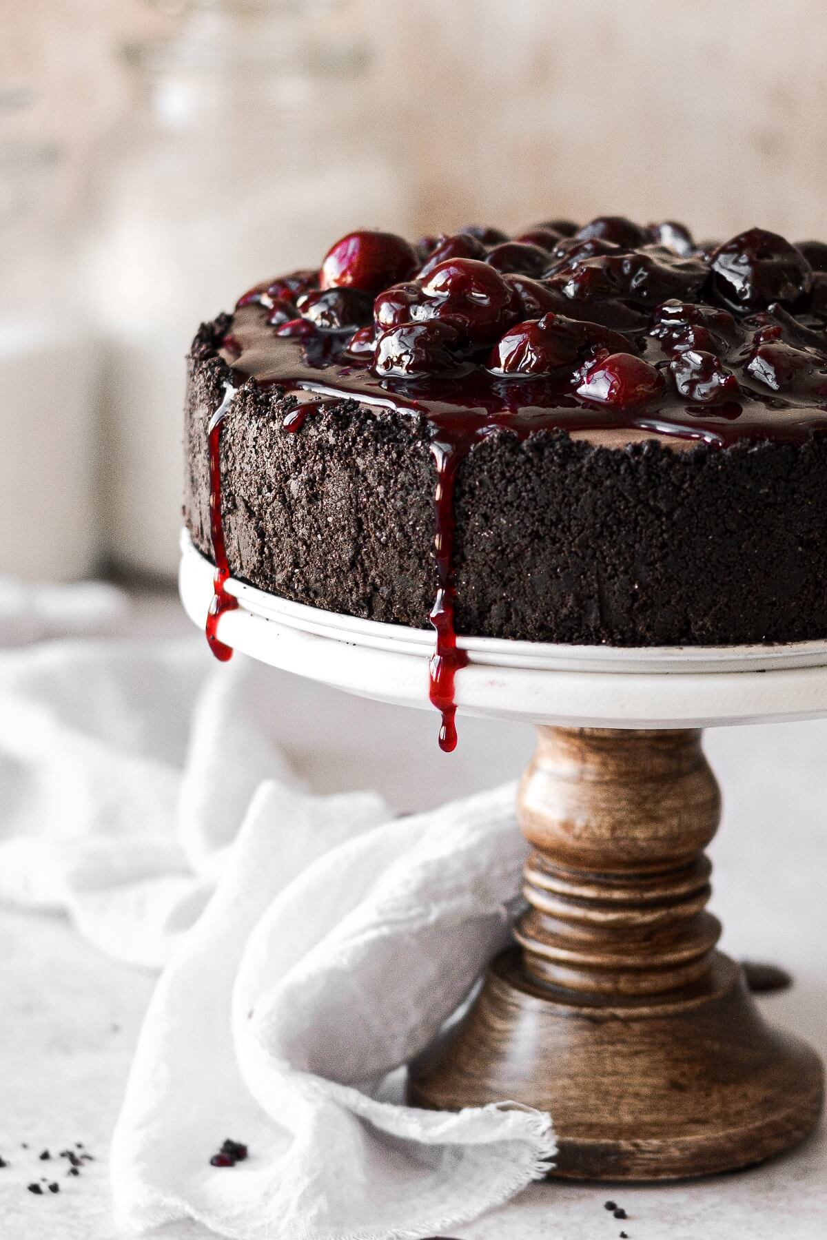 Cherry sauce dripping down the sides of a chocolate cheesecake.