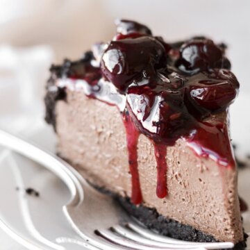 A slice of chocolate cheesecake topped with cherry sauce.