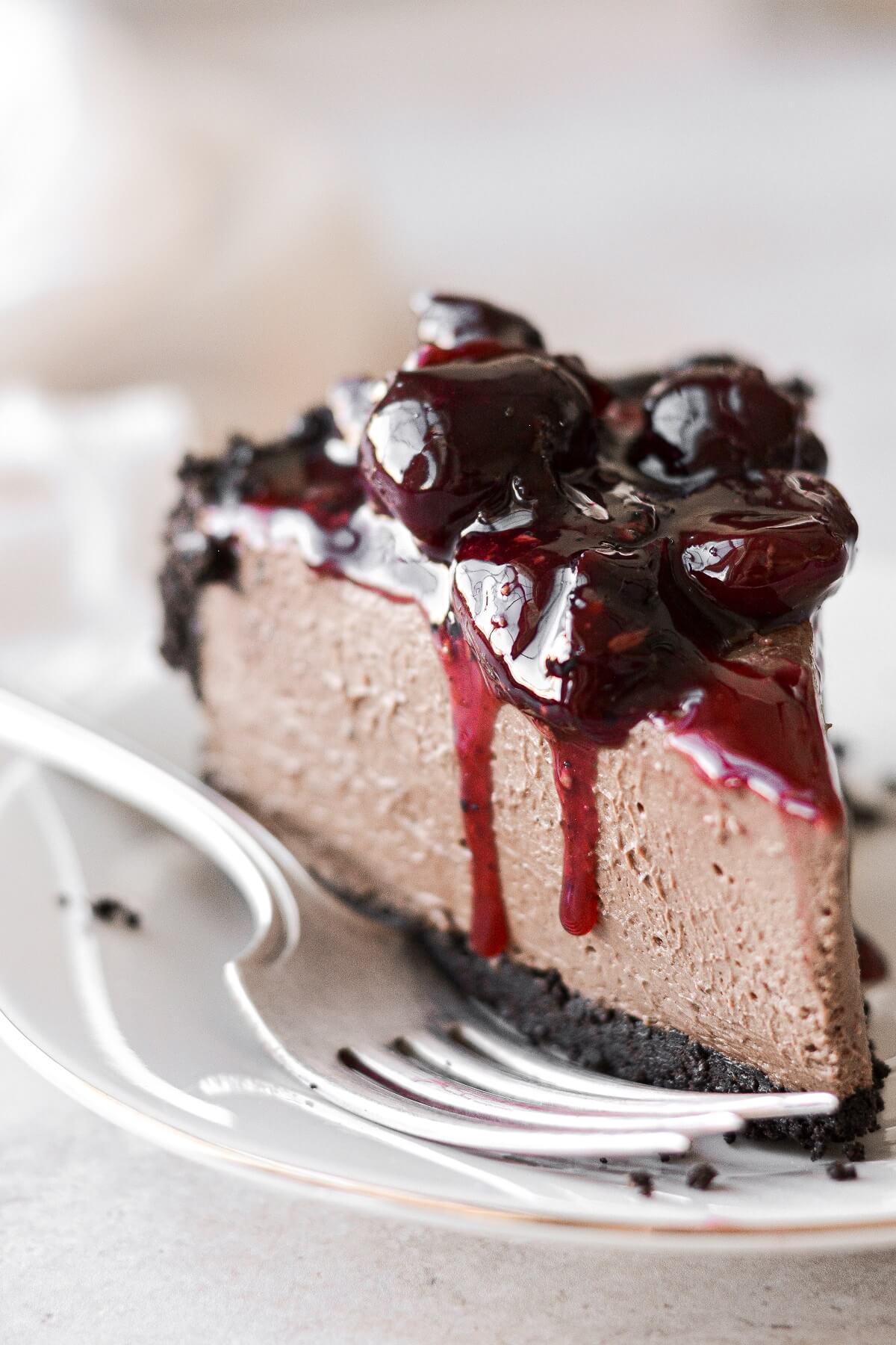 A slice of chocolate cheesecake topped with cherry sauce.
