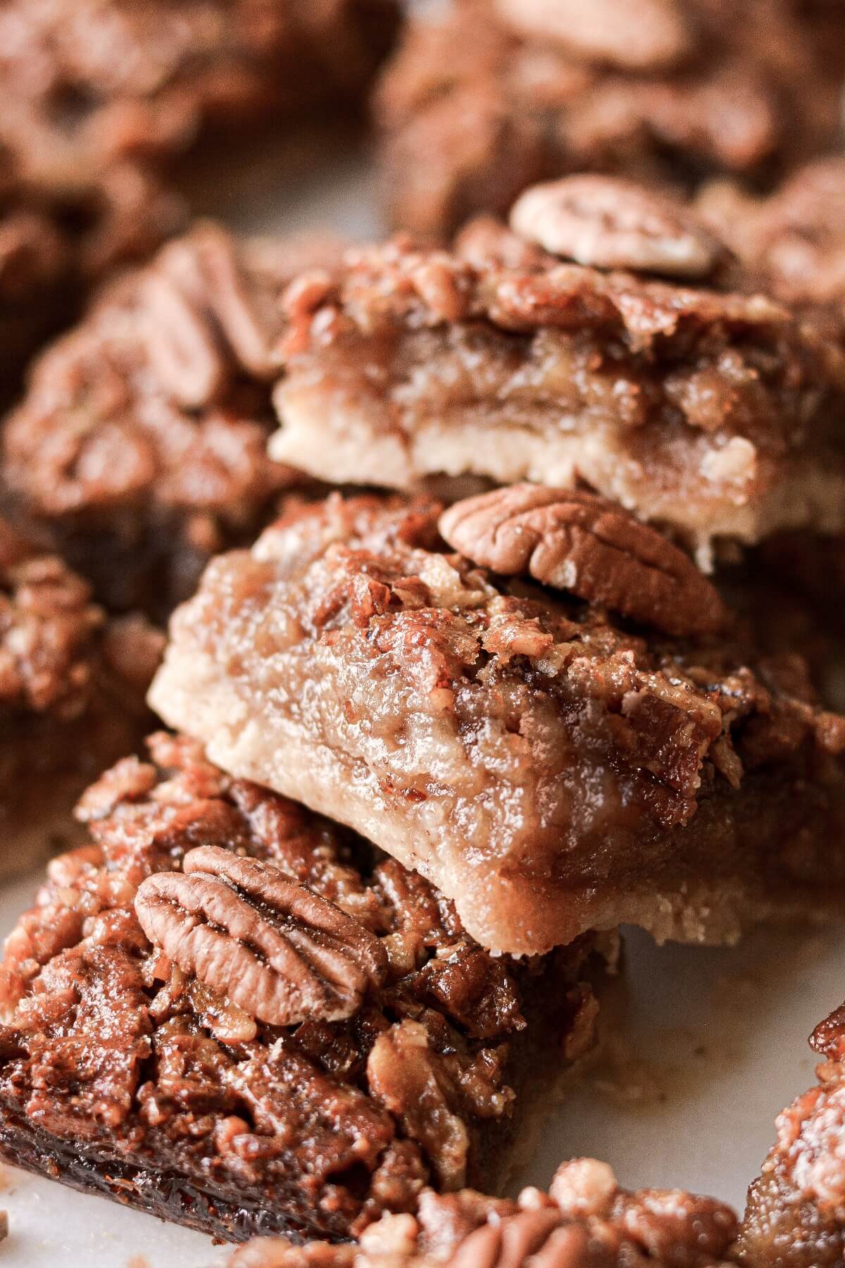 Pecan pie bars with brown butter shortbread crust stacked on a serving board.