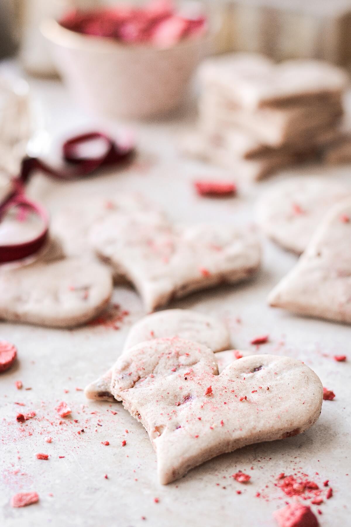 Crushed freeze dried strawberries sprinkled on top of heart shaped shortbread cookies.