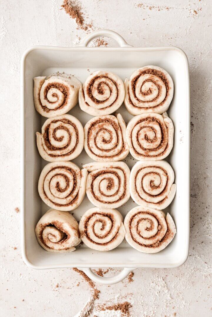 Cinnamon rolls rising in a baking pan.