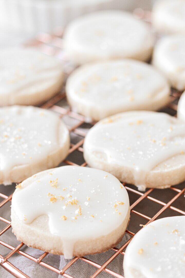 Iced lemon shortbread cookies on a gold cooling rack.