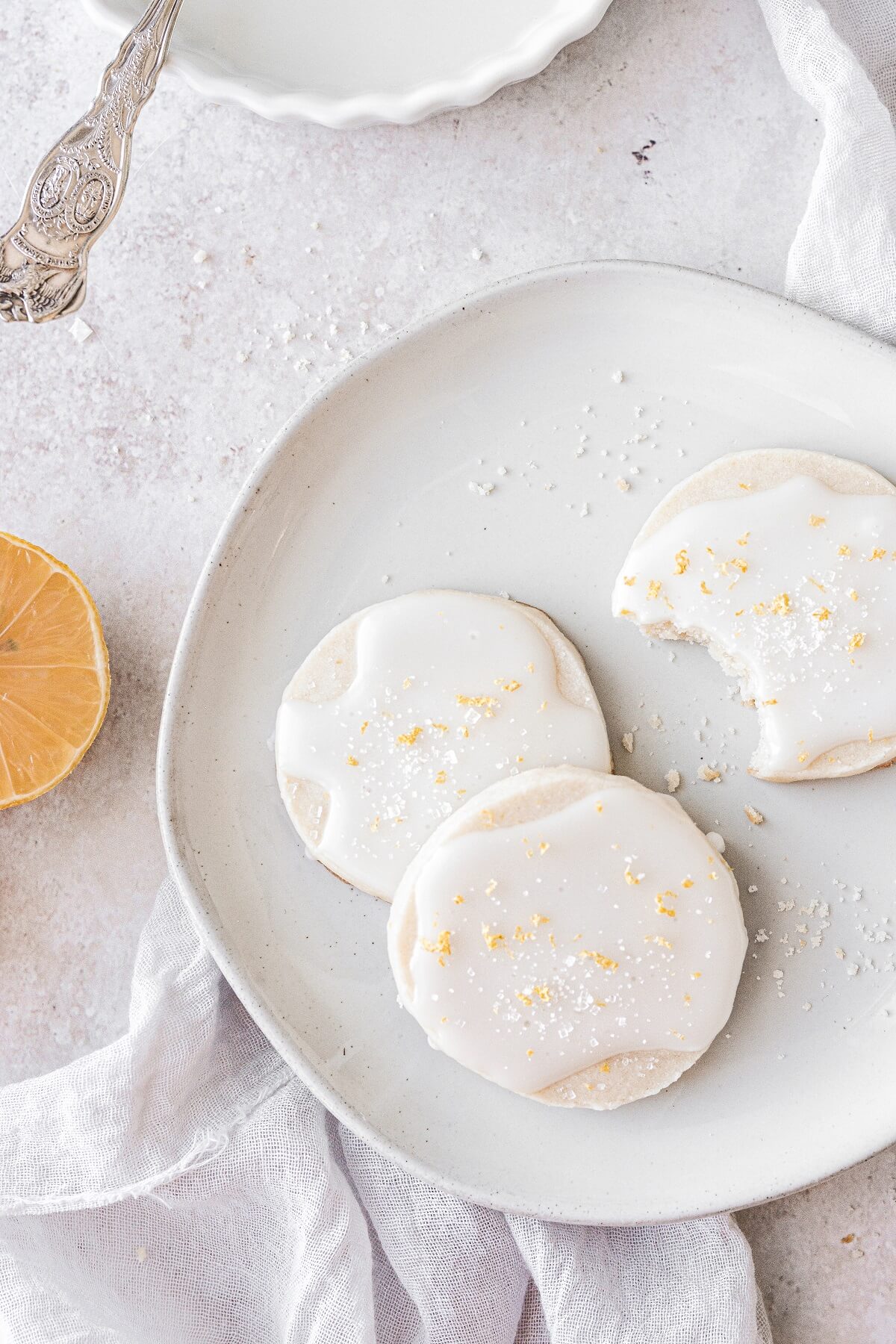 Iced lemon shortbread cookies with a bite taken out of one.