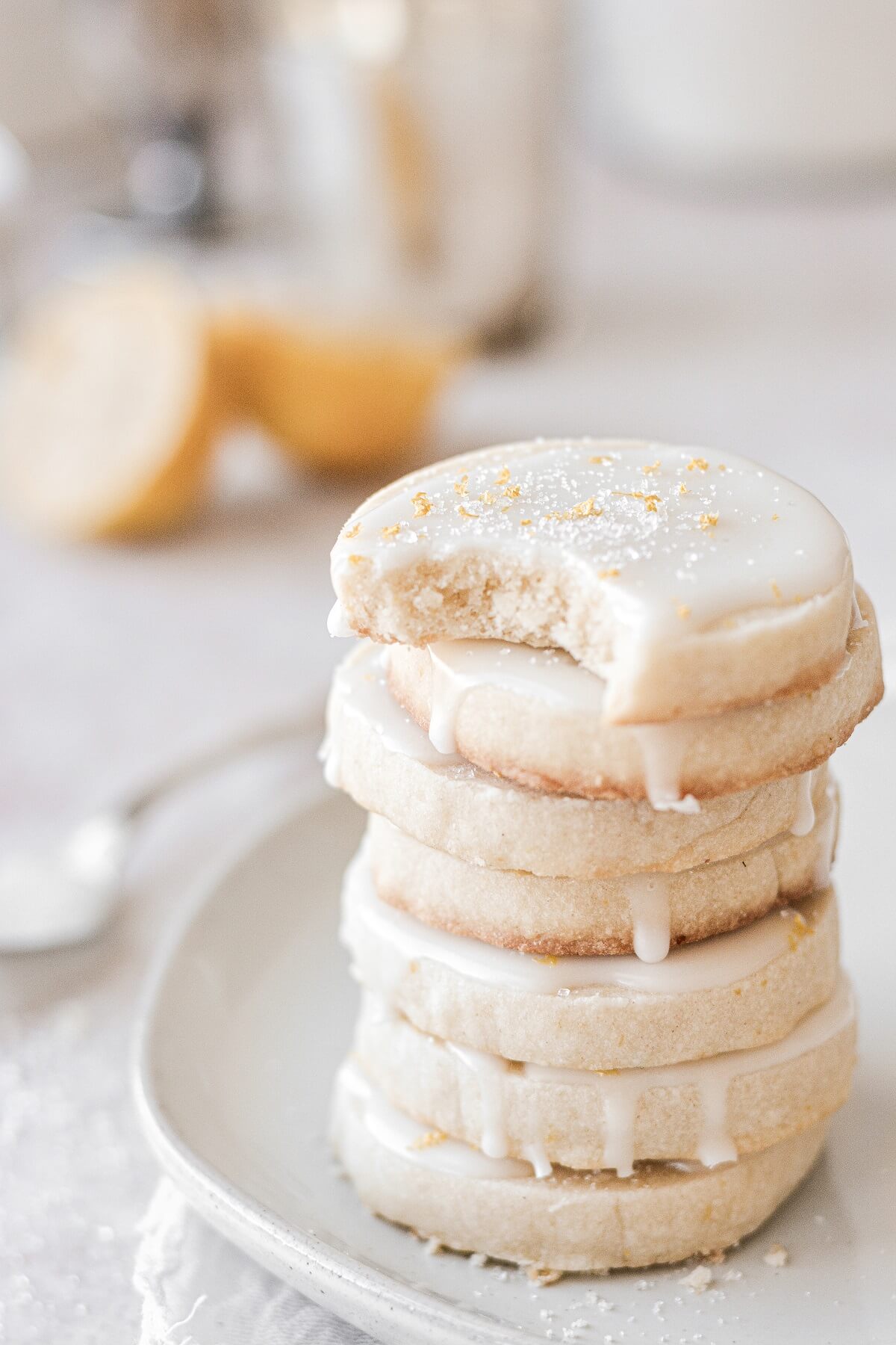 A stack of iced lemon shortbread cookies with a bite taken out of one.