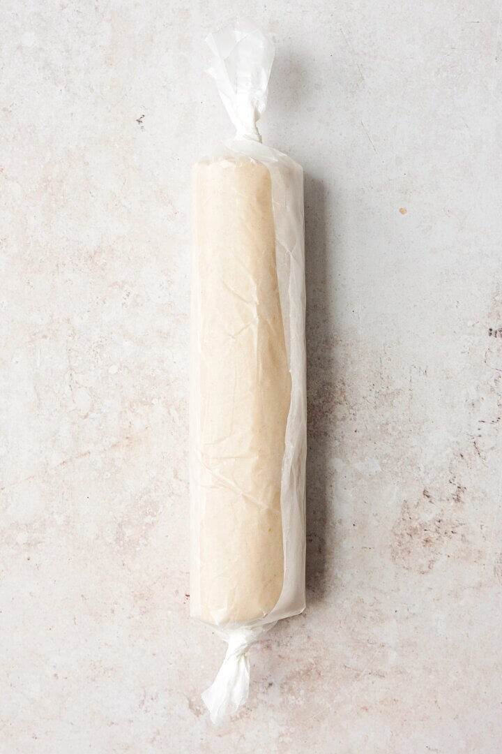 A log of lemon shortbread cookie dough wrapped in wax paper.