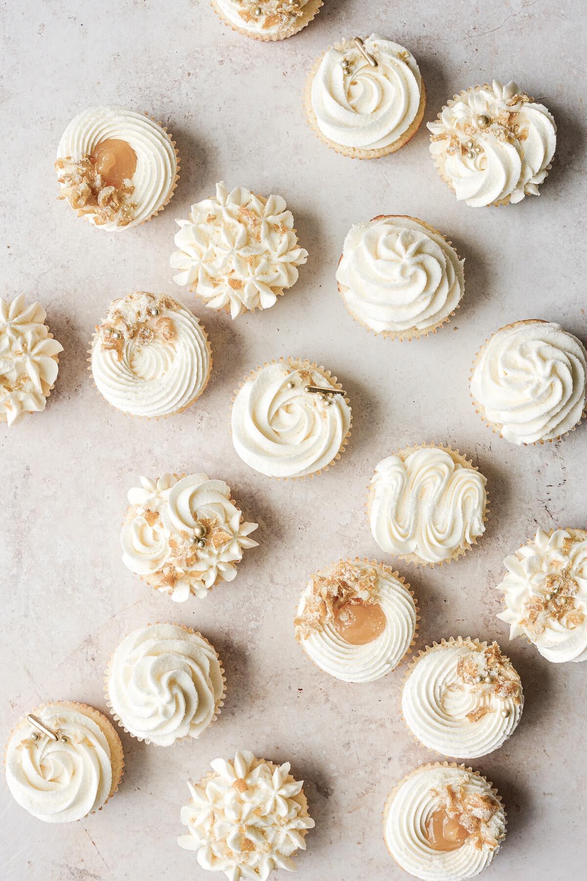 Lemon cupcakes decorated with buttercream, gold sugar pearls and candied lemon peel.