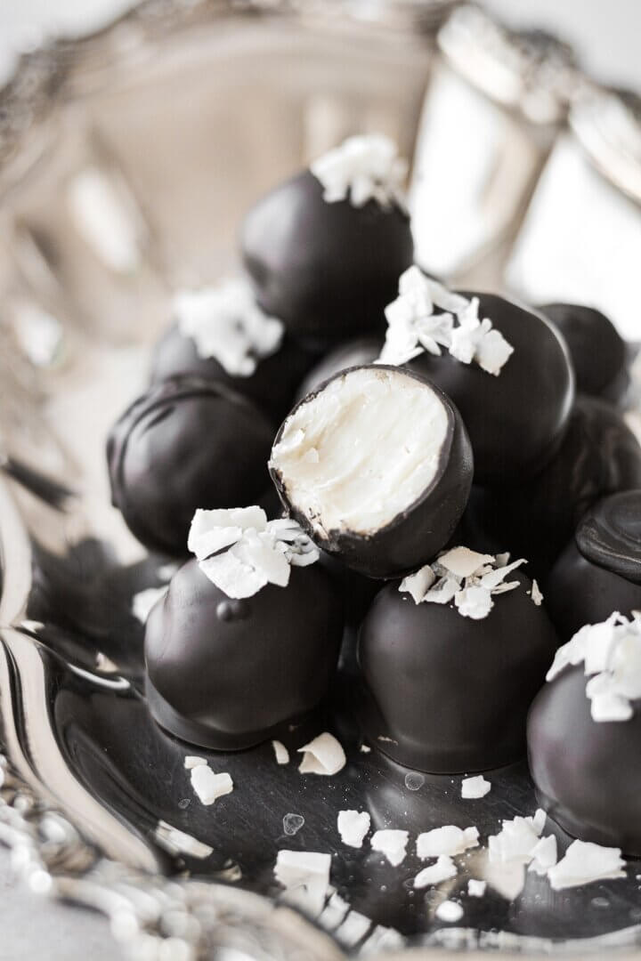 White chocolate coconut truffles, one with a bite taken.